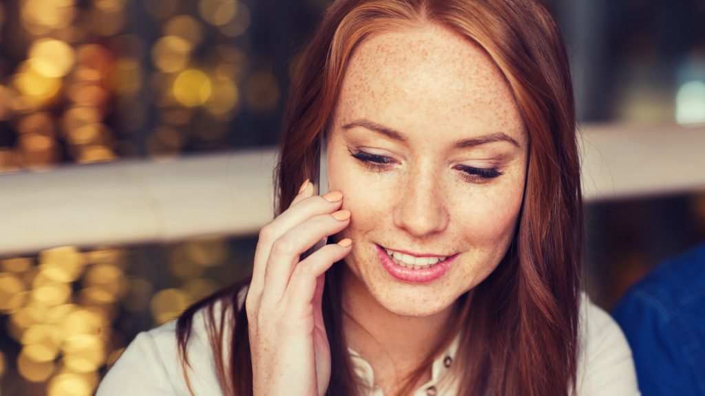 happy woman calling on smartphone at restaurant